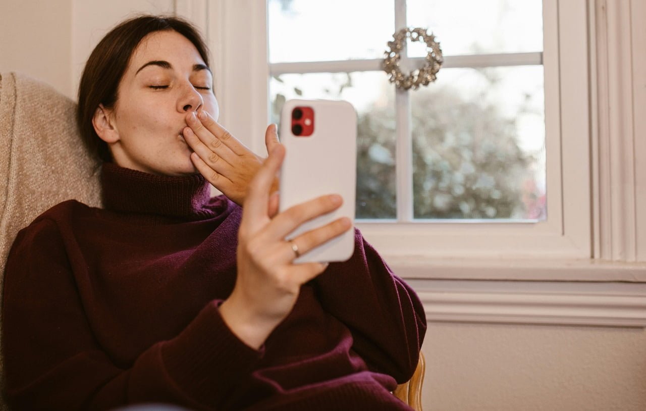 girl holding a phone and sending kiss